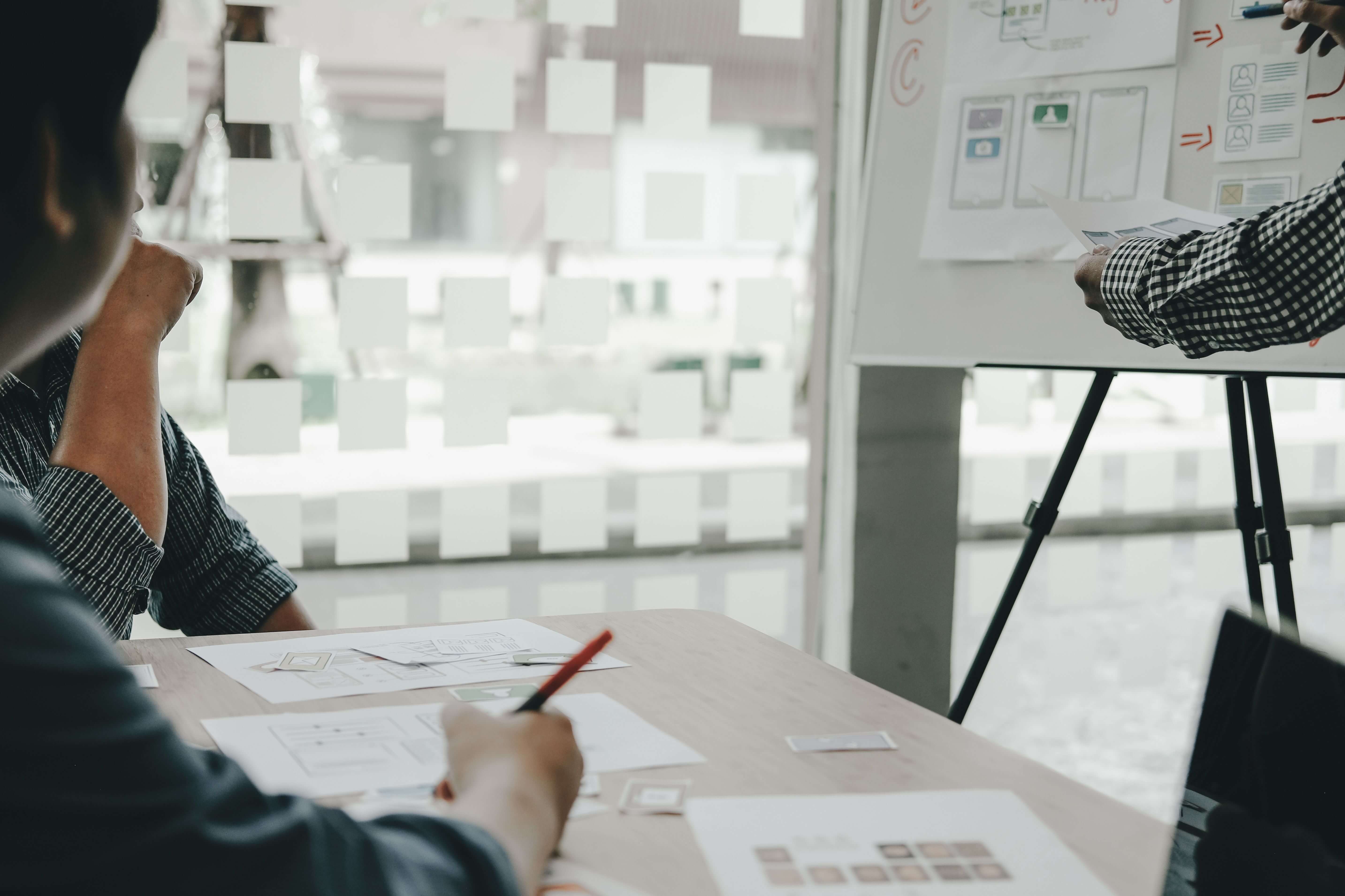 A business meeting with papers stuck on the wall and on a board.